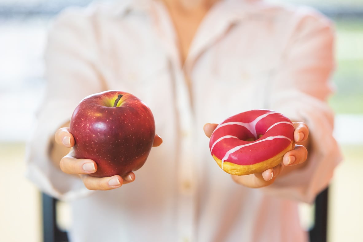 femme qui tient une pomme dans une main et un beigne dans l'autre