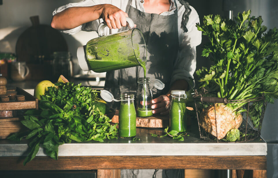 Une personne verse un smoothie vert dans un pot