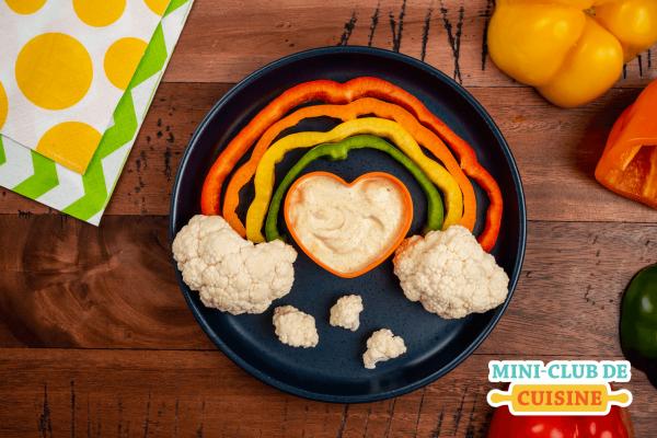 Arc-en-ciel fait de poivrons et avec chou-fleur pour nuage et avec un bol de trempette