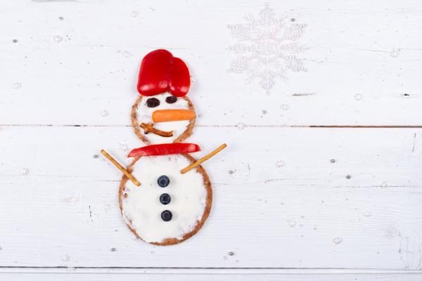 Bonhomme de neige fait avec pain naan et des légumes et fruits pour les yeux, nez et boutons