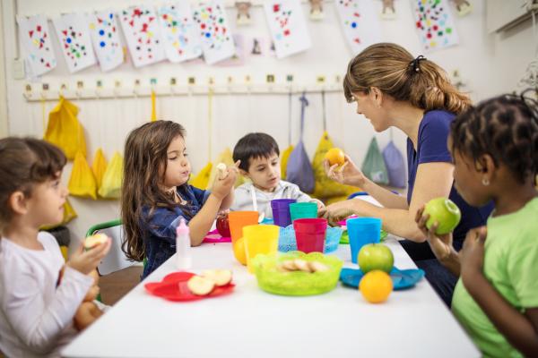 éducatrice assise avec les enfants à table en train de manger