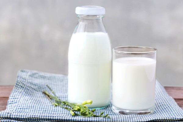 A bottle of milk and freshly-poured glass, sitting on a table