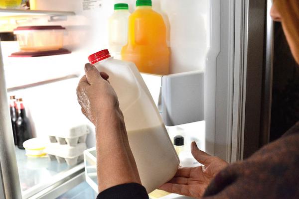 Une femme sort le lait du réfrigérateur à la maison.