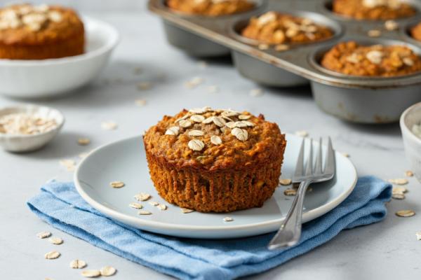 Muffin à l’avoine et aux carottes sur une assiette, avec des flocons d’avoine éparpillés