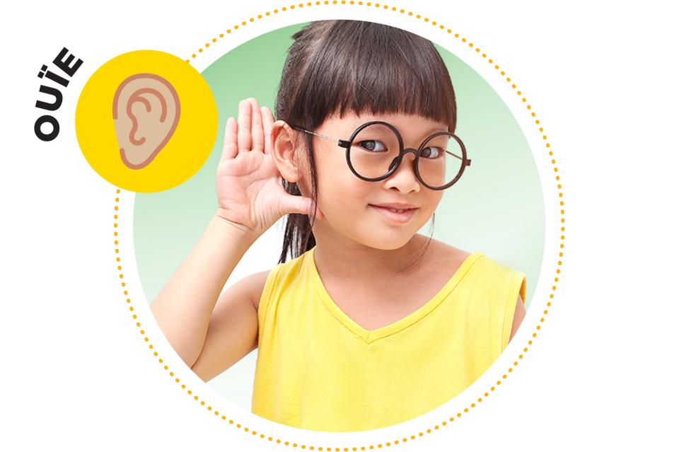 Petite fille portant sa main à son oreille.