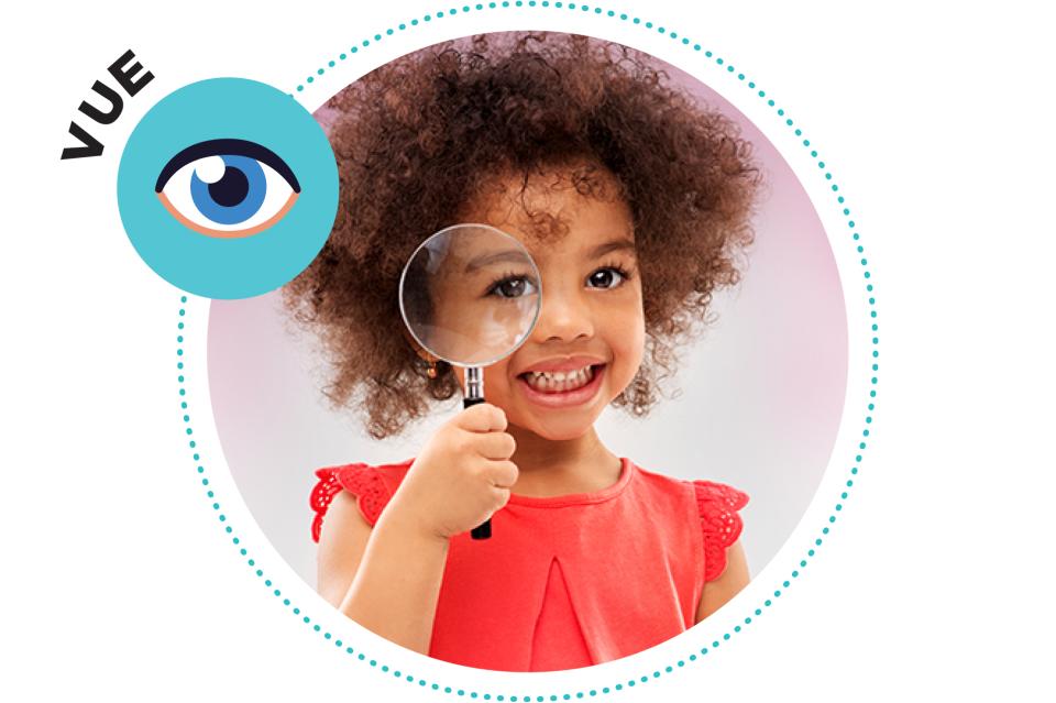 Petite fille tenant une loupe à son œil.