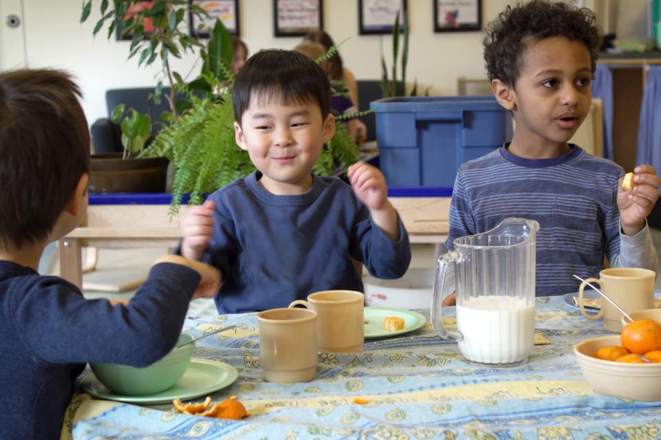 3 garçons qui mangent une collation assis à une table