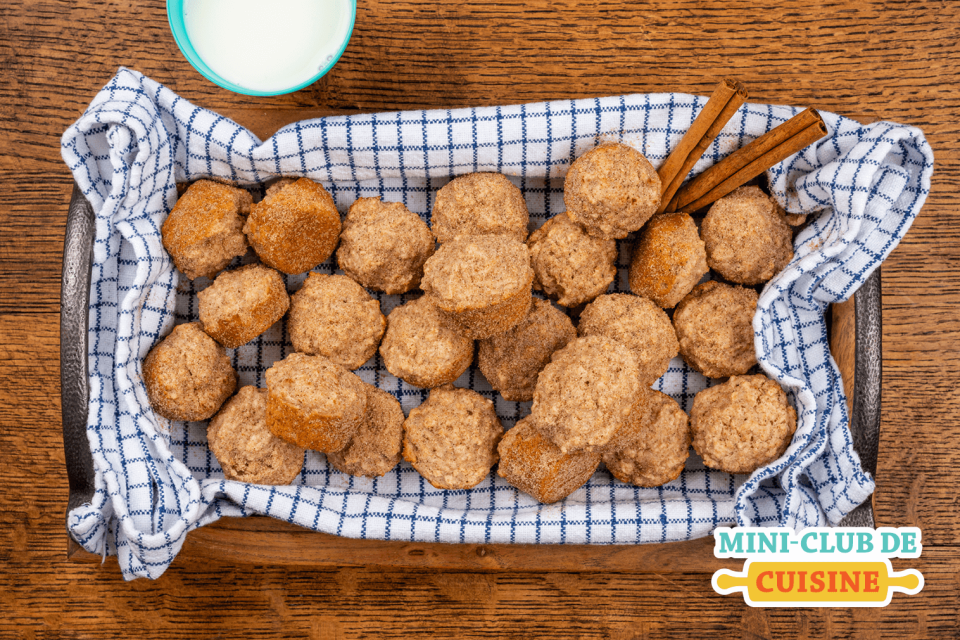 mini muffins à la cannelle dans un panier sur une table de bois avec un verre de lait