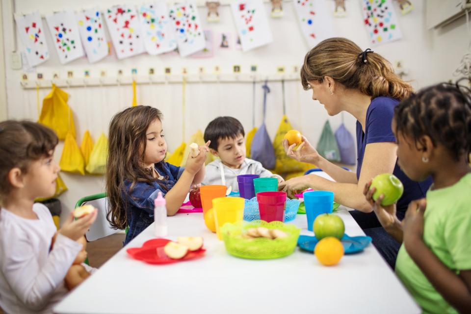 teacher and children sitting at a table and eating