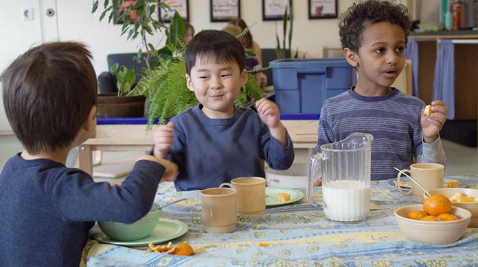 Picture of three pre-school boys sitting around a table eating a snack