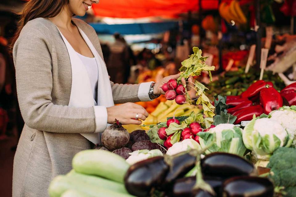 Une femme choisit des fruits et légumes au marché