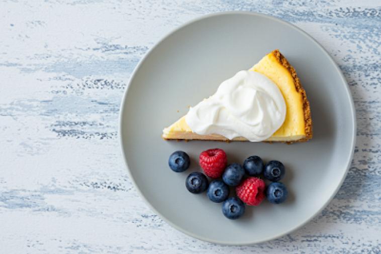 Image de haut en bas d'une assiette de cheesecake avec des baies mélangées sur le côté