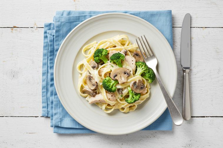 Image de haut de fettuccine alfredo avec poulet, champignons et brocoli sur une assiette
