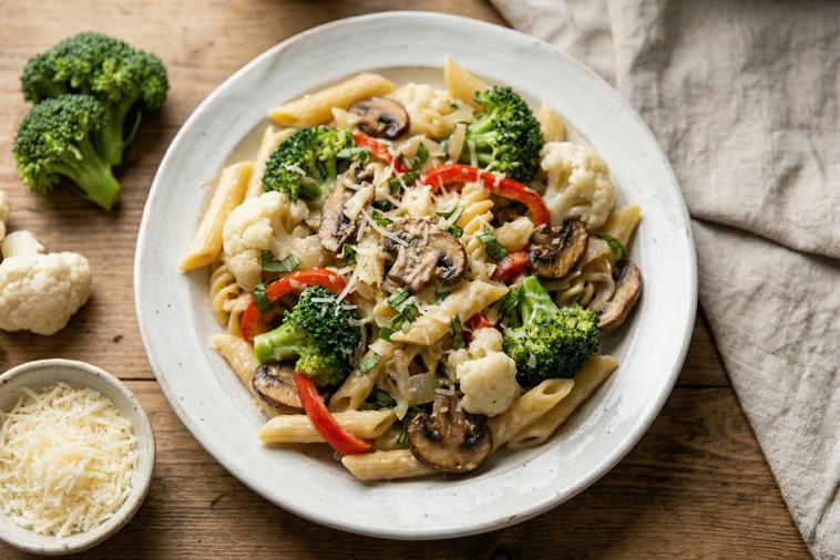 Penne pasta mixed with broccoli, mushrooms, cauliflower, representing a wholesome vegetarian meal